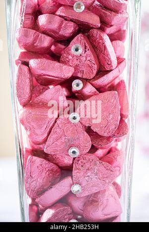 Herzförmige Schokoladen-Bonbons in rosa Aluminiumfolie an der Dessertbar eingewickelt Stockfoto