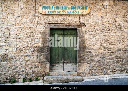 „Moulin et Huilerie du Bon-Pasteur – L. Buisson, Ramos Sr“ steht auf dem Schild über der grünen Holztür des ehemaligen Mühlengebäudes in Draguignan, Departement Var, Frankreich; erstmals 1379 urkundlich erwähnt, wurde die Mühle 1874 in eine Ölmühle umgewandelt und 1923 von Léonce Buisson übernommen, der sie bis zu ihrer endgültigen Schließung im Jahr 1965 betrieb. Stockfoto