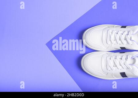 Flache Laie von Sport-Sneakers-Schuhen auf dem blau-lila Hintergrund. Fitness-Hintergrund. Gesundes Lifestyle-Konzept. Trendige Farben. Farbe 2022. Farbe Stockfoto