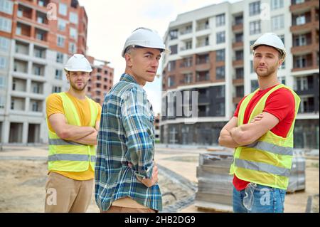 Techniker und zwei Arbeiter, die die Kamera betrachten Stockfoto
