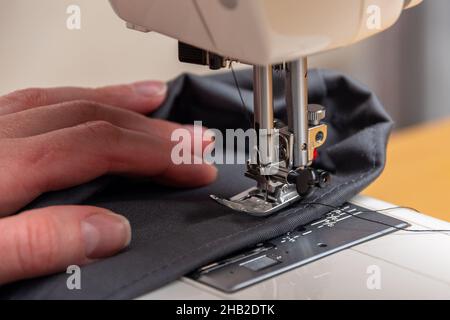 Nähprozess. Nahaufnahme der Reparatur von Kleidung, Nähen auf einer Nähmaschine. Reparaturkonzept für Kleidung. Konzept zur Reduzierung des Verbrauchs. Pflege der Umwelt Stockfoto