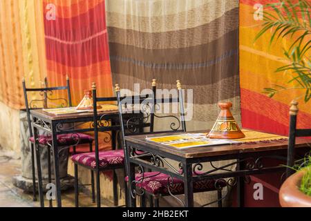 Straßenrestaurant oder Café mit morokochensäurehaltendem, traditionellem Tagine-Kochgeschirr auf dem Tisch Stockfoto