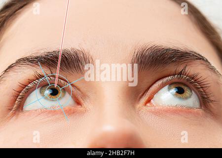 Nahaufnahme der Augen der Frau, die nach oben schauen, und Laserstrahl-Beleuchtung bei der Pupille des Auges. Das Konzept der Laser-Augenchirurgie und Augenheilkunde. Stockfoto