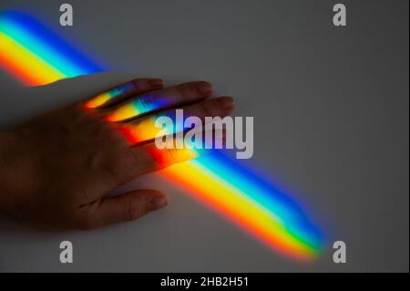 Regenbogenstrahl auf der Hand einer Frau. Stockfoto