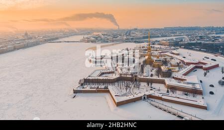 Drohne Sicht des Winters St. Petersburg bei Sonnenuntergang, gefrorener Neva Fluss, Dampf über der Stadt, Peter und Paul Festung, Autoverkehr auf Trinity Brücke Stockfoto