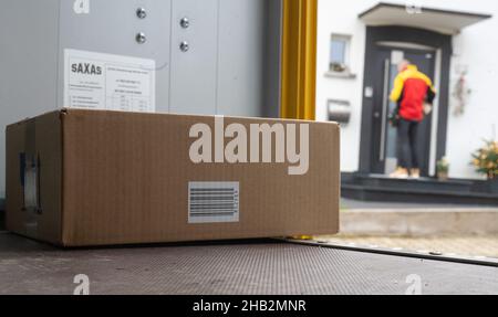 Ober Ramstadt, Deutschland. 15th Dez 2021. Ein DHL-Mitarbeiter liefert ein Paket aus. Im Vordergrund ist ein weiteres Paket in seinem Van. (To dpa 'Deliverers carry out Millions of parcels before Christmas') Quelle: Sebastian Gollnow/dpa/Alamy Live News Stockfoto