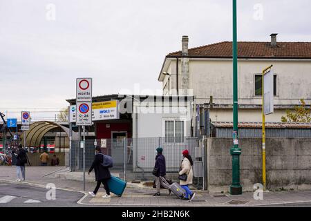 Drei Touristen laufen mit ihren Koffern während der Corona-Pandemie auf dem Bürgersteig vor einem Bahnhof. Alle tragen Corona-Schutzmasken. Stockfoto