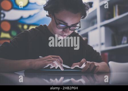 Teenager zeichnen mit Tablet und virtuellem Stift. Schüler der Millennials machen Hausaufgaben mit neuen Technologiegeräten. Kleiner Junge zeichnen auf Pad zu Hause. Männliche Hände Stockfoto