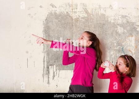Zwei kleine Mädchen nehmen Bild mit Spielzeug-Fotokamera auf grauem Hintergrund Stockfoto