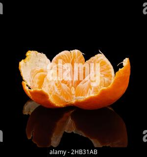 Reife Mandarine, halb geschält, schwarzer Hintergrund mit Spiegelung Stockfoto