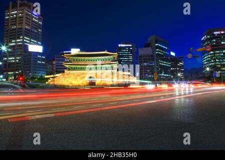 Namdaemun Gate oder Sungnyemun Gate zur blauen Stunde mit leichten Wegen von Fahrzeugen. Dieses historische Gebäude ist von hohen modernen Gebäuden umgeben. Stockfoto