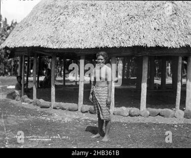 Samoan Village, in der Nähe von Apia, Burton Brothers Studio, Fotostudio, 19. Juli 1884, Neuseeland, Schwarz-Weiß-Fotografie, samoanische Frau, die vor einem sehr großen Fal steht, große Steine laufen um den Rand. Geflochtenes Dach mit offenen Seiten, mattgeflammte Jalousien werden aufgerollt Stockfoto