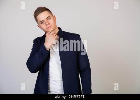 Hübscher junger Mann mit stilvoller Frisur, der mit einem Lächeln auf dem Gesicht auf die Kamera blickt. Foto von jungen attraktiven schönen modernen Freiberufler Stockfoto