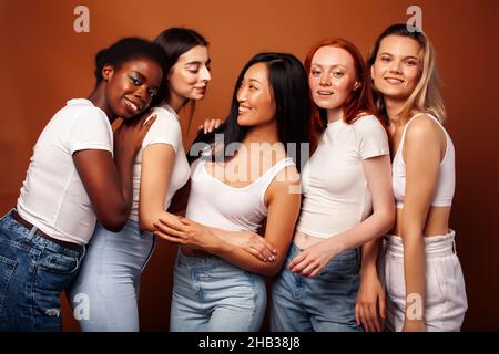 Junge hübsche kaukasische, afro, skandinavische Frau posiert fröhlich zusammen auf braunem Hintergrund, Lifestyle diverse Nationalität Menschen Konzept Stockfoto