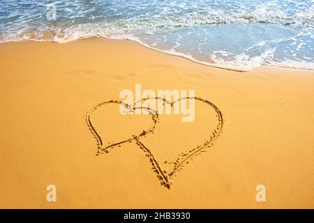 Zwei Herzen handgeschrieben auf Sand des tropischen Strandes, Hintergrund Stockfoto