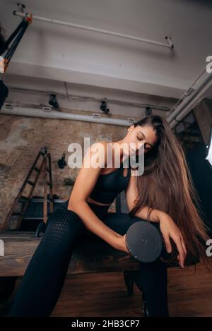 Junge Frau pumpt die Muskeln mit einem Arm Hantel heben. Stockfoto