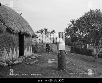 Tongan Woman, Nukualofa [Nuku'alofa], Burton Brothers Studio, Fotostudio, 29. Juli 1884, Neuseeland, Schwarz-Weiß-Fotografie, Frau, die vor Fale seitlich steht, mit Tür direkt hinter ihr. Ein kleineres Fale liegt dahinter. Nach rechts kleiner Baum und ein Zaun Stockfoto