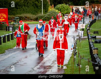 Viele Santas, die in einem Santa Dash einen Hügel hochlaufen Stockfoto