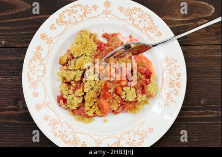 Plum bröckelt auf weißem Teller auf dunklem Holzhintergrund von oben Stockfoto