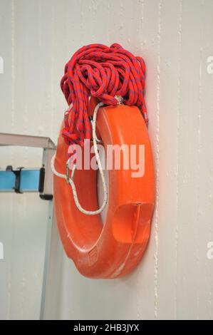 Vertikale Aufnahme eines roten Rettungsringes, der an der Wand hängt Stockfoto