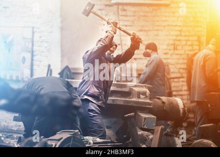 Arbeiter schwingt großen Hammer in der Werkstatt der metallurgischen Anlage. Stockfoto