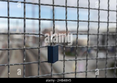 Vorhängeschlösser, die an einem Drahtseil hängen. Liebesschlösser am Gitterzaun an der Brigde in New Wesminster BC. Blick auf die Straße, niemand, selektiver Fokus, verschwommenes Backgro Stockfoto