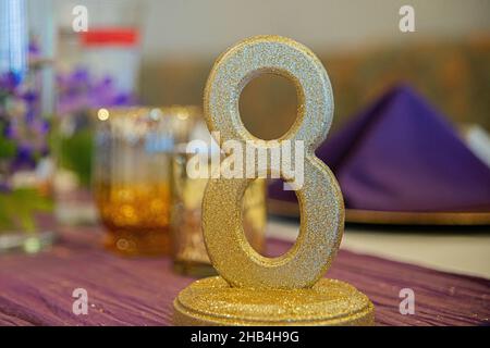 Goldenes Schild mit der Nummer acht für den Gästeplatz am eleganten Hochzeitstisch Stockfoto