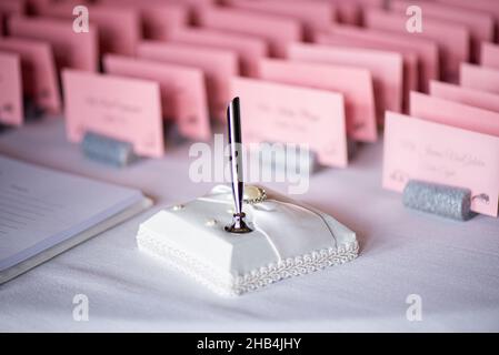 Weißer Stifthalter am Schild für Hochzeitsgäste am Tisch Stockfoto