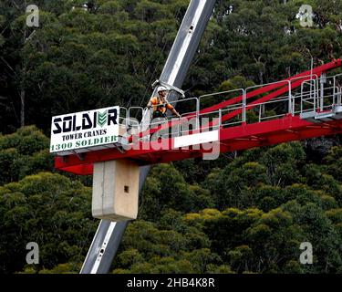 8:10 Uhr 7. Dezember 2021: Gosford, NSW, Australien. Arbeiter demontieren den Turmdrehkran vor Ort (Entfernen der Gegengewichte) auf dem fertig gestellten sozialen Netzwerk Stockfoto