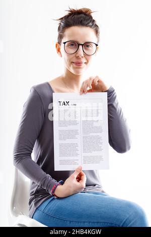 Die Frau saß auf einem weißen Plastikstuhl und zeigte mit einem leicht schlauen Lächeln ein Steuerformular Stockfoto