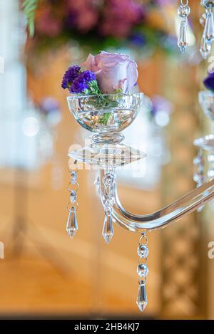 Dekorative Kerzenhalter aus Glas mit Kristallen gefüllt mit rosa Rosen Stockfoto