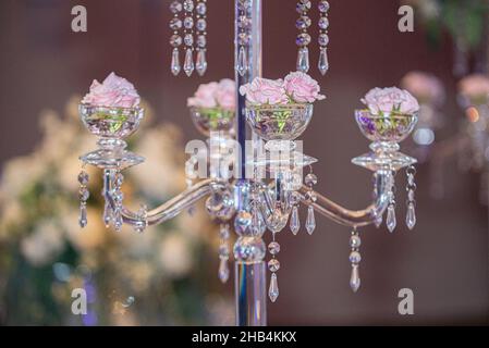 Dekorative, elegante Kerzenstangenhalter aus Glas mit Kristallen gefüllt mit rosa Rosen Stockfoto