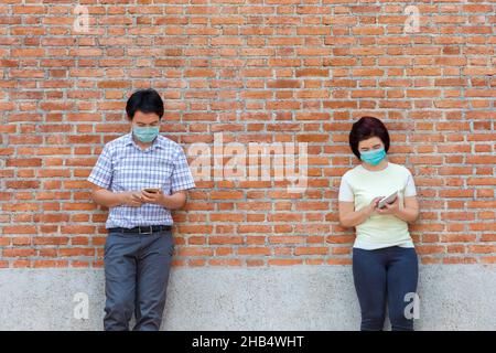 Asiatische Menschen mittleren Alters tragen Maske und halten soziale Distanzierung, um die Ausbreitung von COVID-19 zu vermeiden Stockfoto