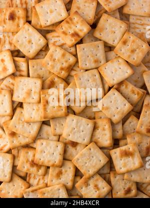 Käsegebäck im Hintergrund, knusprige und quadratische Cracker, Tee-Time-Snack von oben, Nahaufnahme Stockfoto