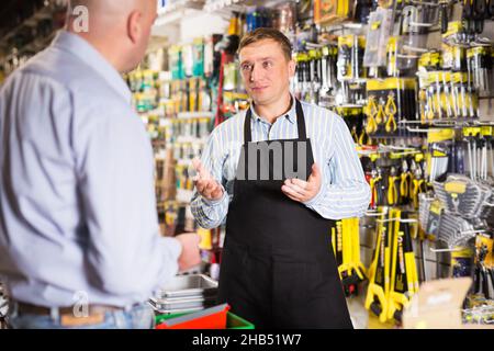 Verkäufer, der dem Mann im Geschäft Werkzeuge anbietet Stockfoto