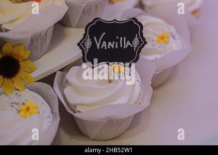 Cupcakes aus Vanille mit Schokoladenbröseln Cupcakes mit Schild an der Dessertbar Stockfoto