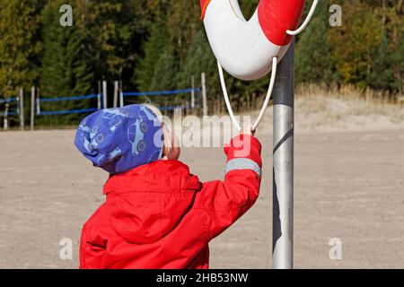 Umea, Norrland Schweden - 9. September 2019: Ein kleiner Kerl überprüft die Sicherheitsausrüstung am Strand Stockfoto