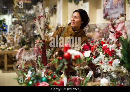 Positive asiatische Frau wählt eine Weihnachtskomposition Stockfoto