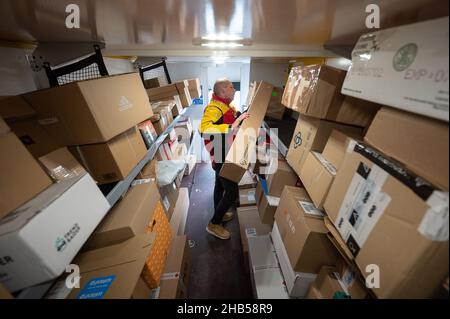 Ober Ramstadt, Deutschland. 15th Dez 2021. Ein DHL-Mitarbeiter sortiert Pakete in seinem Van für die nächsten Lieferungen. Quelle: Sebastian Gollnow/dpa/Alamy Live News Stockfoto