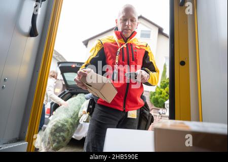 Ober Ramstadt, Deutschland. 15th Dez 2021. Ein DHL-Mitarbeiter scannt ein Paket zur Lieferung. Quelle: Sebastian Gollnow/dpa/Alamy Live News Stockfoto