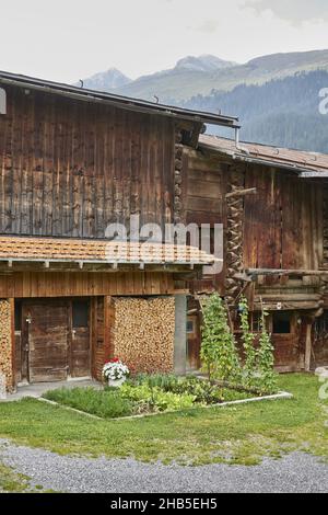 Holzhaus mit einem schönen Garten draußen von riesigen Bäumen bedeckten Bergen an einem nebligen Tag umgeben Stockfoto