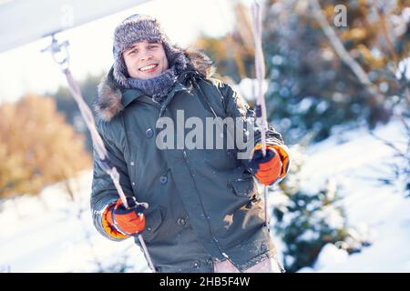 Junger, hübscher Mann, der sich in der Winterlandschaft auf Schaukel amüsieren kann Stockfoto