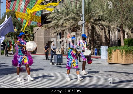 Dubai, VAE, 09.12.2021. Expo 2020 Dubai Daily Parade, Musiker spielen Schlagzeug, tragen bunte Expo 2020-Themen-Kleidung und Fahnen. Stockfoto