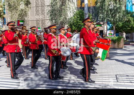 Dubai, VAE, 09.12.2021. Dubai Police Brass Band Orchester tritt auf der Expo 2020 Dubai Daily Parade auf, Männer in roten Suiten tragen die VAE-Nationalmannschaft Stockfoto