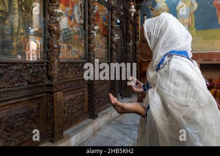 Eine äthiopisch-orthodoxe Christin betet vor der Ikonostase in der griechisch-orthodoxen Kirche der Verkündigung, auch bekannt als die Kirche des heiligen Gabriel oder die griechisch-orthodoxe Kirche des heiligen Gabriel in der Stadt Nazareth, Nordisraelien Stockfoto