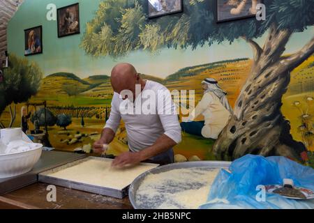 Ein arabisch-israelischer Mann bereitet in seinem Laden in der Altstadt von Nazareth, Nordisrael, das traditionelle nahöstliche Knafeh oder Kenafeh-Vergnügen zu Stockfoto