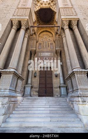 Seitentor an der al Rifai Moschee, alte verzierte Ziegelsteinmauer mit Arabesken verzierten Holztüren, umrahmt von zylindrischen Marmorsäulen, mittelalterliches Kairo Ägypten Stockfoto