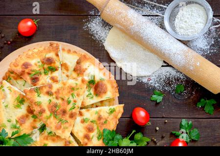 Stücke khachapuri mit Hüttenkäse und Kräutern auf einem Brett. Georgisches Gebäck. Draufsicht, flach liegend Stockfoto