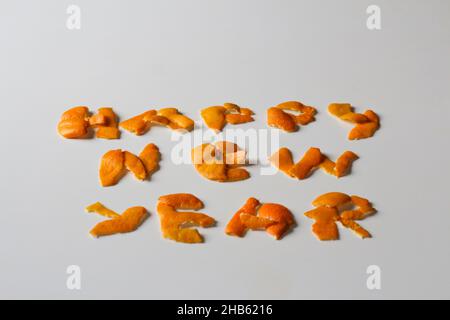 Unschärfe-Effekt Neujahrs-Wort, dargestellt durch trockene Orangenhaut auf einem isolierten weißen Hintergrund. Dekoration für Silvester, Konzept. Grußkarte. Text und DIY Stockfoto