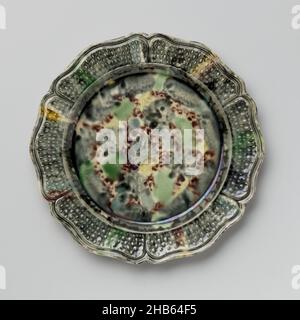Platte aus mehrfarbiger hartgebrannter Keramik; Staffordshire, Platte aus mehrfarbiger hartgebrannter Keramik, mit einem gefalztem Rand. Der Rand ist mit sechs Feldern aus gewelltem Gitter im Relief verziert. Die Platte ist mit einer blau-grauen Bleiglasur mit Flecken in Grün, Gelb und Mangan bedeckt. Die Rückseite ist mit Mangan übersät. Vier Platten begleiten die Platte., anonym, England, c. 1750 - c. 1780, Steingut, Bleiglasur, Höhe 2,0 cm × Durchmesser 23,0 cm Stockfoto